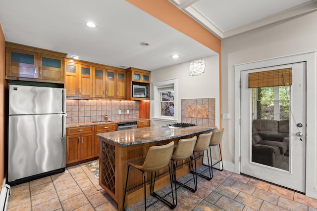 152 Algonquin Ave, Mashpee, MA 02649 - kitchen featuring appliances with stainless steel finishes, brown cabinets, backsplash, dark stone countertops, and a peninsula
