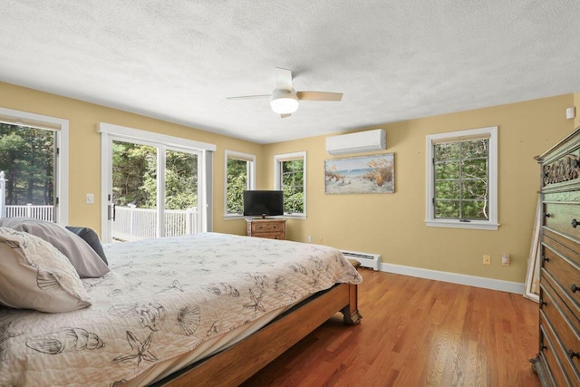 34 Marla Ln, Hatchville, MA 02536 - bedroom with a wall mounted AC, baseboard heating, access to outside, a textured ceiling, and light wood finished floors