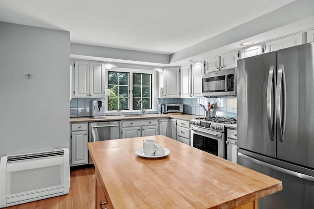 34 Marla Ln, Hatchville, MA 02536 - kitchen with appliances with stainless steel finishes, a sink, heating unit, decorative backsplash, and light wood-style flooring
