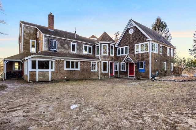 rear view of property with a chimney and a gambrel roof