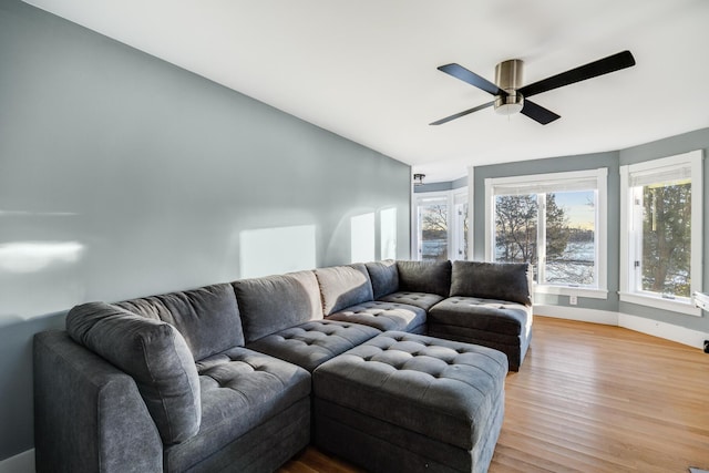 living area with a ceiling fan, lofted ceiling, baseboards, and light wood finished floors