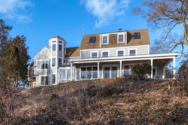 rear view of property with a shingled roof and a chimney