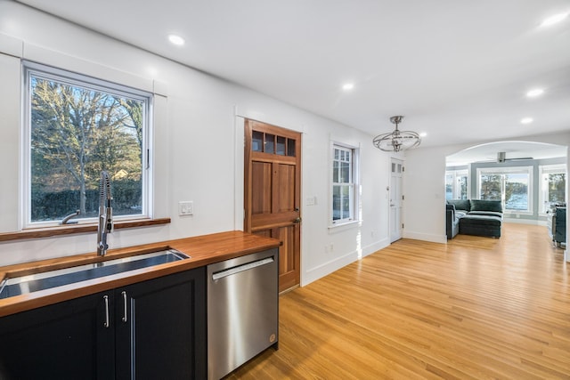 kitchen featuring butcher block counters, a sink, open floor plan, stainless steel dishwasher, and dark cabinetry