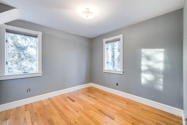 empty room with lofted ceiling, wood finished floors, and baseboards