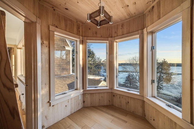 unfurnished sunroom featuring a water view and wood ceiling