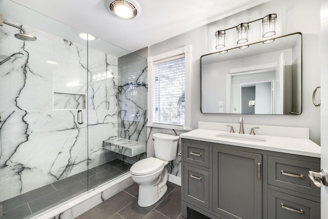 bathroom featuring toilet, tile patterned floors, a marble finish shower, and vanity