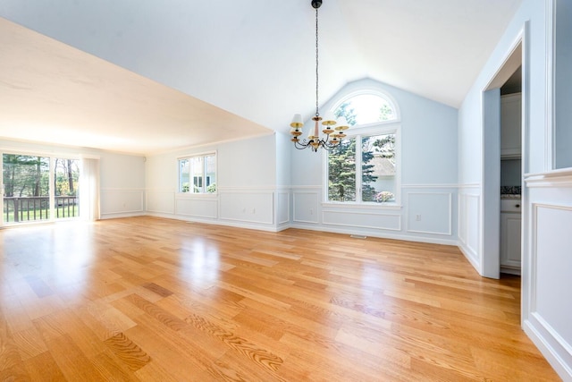 unfurnished dining area featuring a decorative wall, a notable chandelier, plenty of natural light, and a wainscoted wall