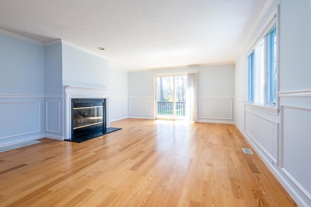 unfurnished living room with visible vents, a glass covered fireplace, and a decorative wall