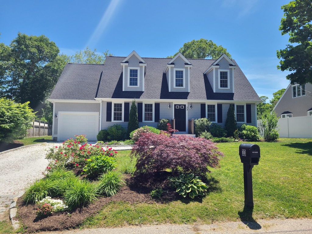 new england style home featuring a garage and a front lawn