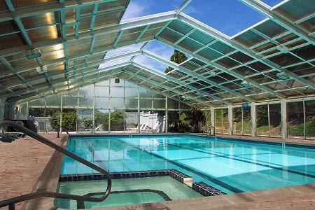 view of pool featuring glass enclosure and an indoor hot tub