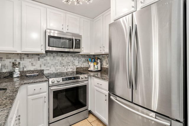 kitchen featuring white cabinetry, dark stone counters, light tile patterned floors, and stainless steel appliances