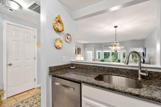 kitchen featuring sink, light tile patterned flooring, stainless steel dishwasher, and dark stone counters