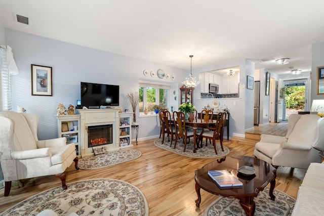 living room with light wood-type flooring and an inviting chandelier