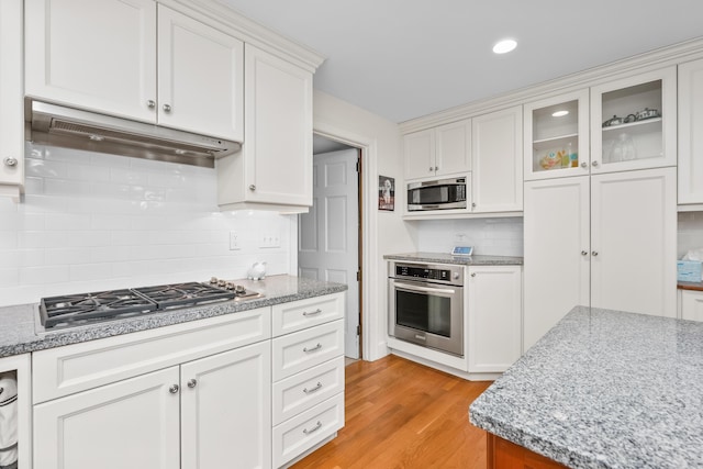 105 Rolling Hitch Rd, Centerville, MA 02632 - kitchen featuring decorative backsplash, white cabinetry, appliances with stainless steel finishes, light wood finished floors, and under cabinet range hood
