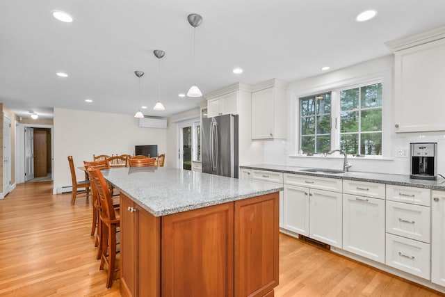 105 Rolling Hitch Rd, Centerville, MA 02632 - kitchen featuring a center island, a sink, light wood-style floors, light stone countertops, and freestanding refrigerator