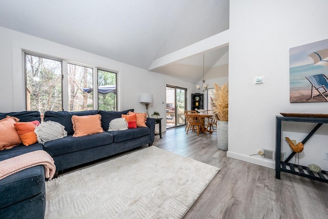 living room featuring baseboards, an inviting chandelier, light wood finished floors, and high vaulted ceiling