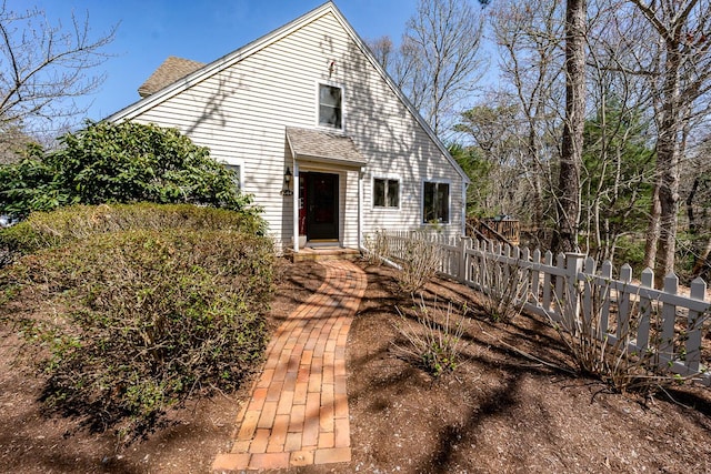 exterior space with roof with shingles and fence