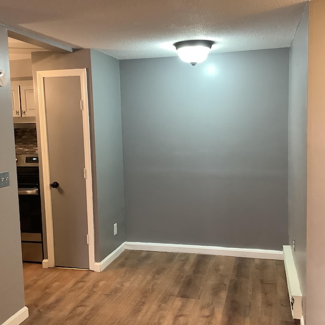 empty room with wood-type flooring and a textured ceiling