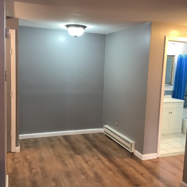 spare room featuring a baseboard radiator, sink, a textured ceiling, and light hardwood / wood-style floors