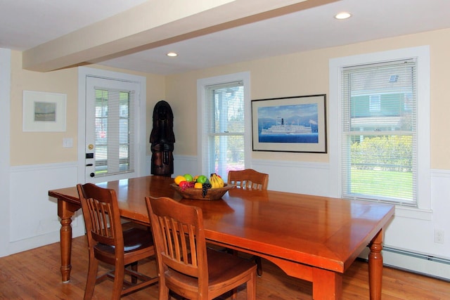 dining area with a baseboard heating unit, a wealth of natural light, light wood finished floors, and wainscoting