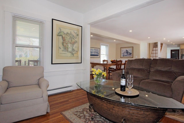 living room with a baseboard heating unit, stairs, and dark wood-style flooring