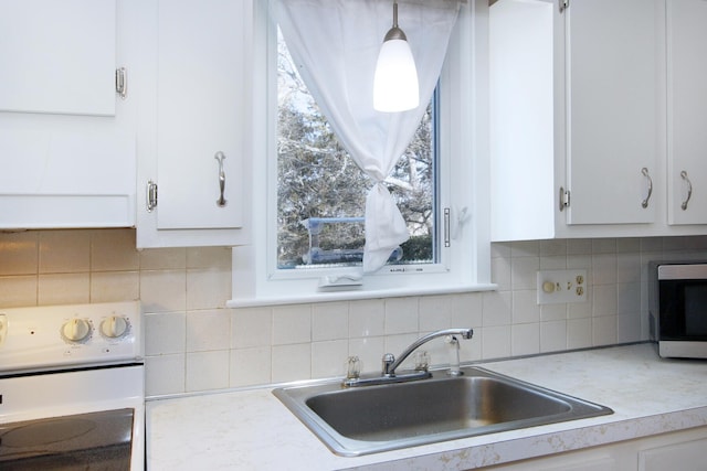 kitchen featuring white cabinetry, pendant lighting, and white electric range