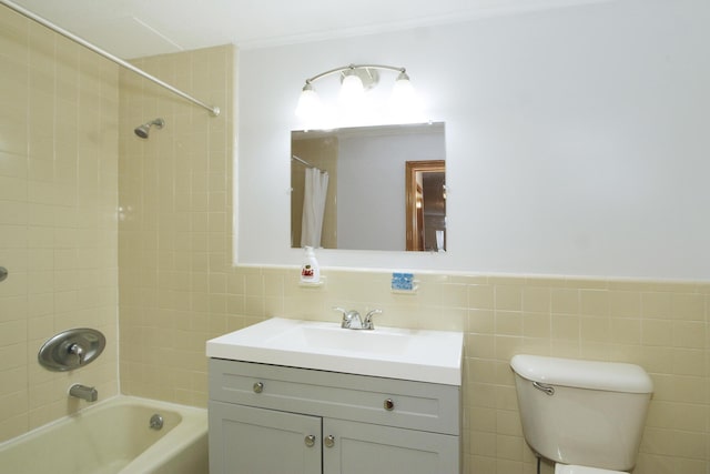 full bathroom featuring vanity, toilet, tiled shower / bath, and tile walls