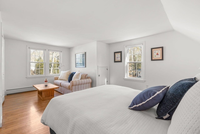 bedroom with lofted ceiling, multiple windows, baseboard heating, and wood finished floors