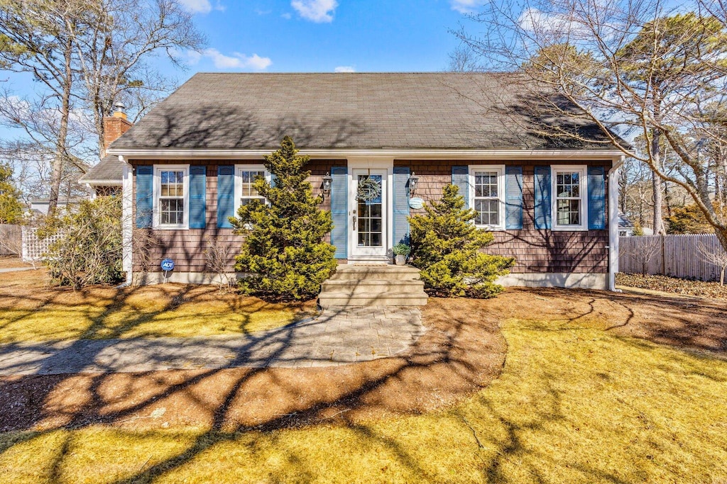 21 Nehoiden Rd, Mashpee, MA 02649 - view of front facade with a chimney, fence, and a front lawn