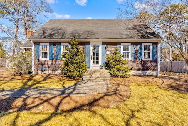 view of front facade with a chimney, fence, and a front lawn