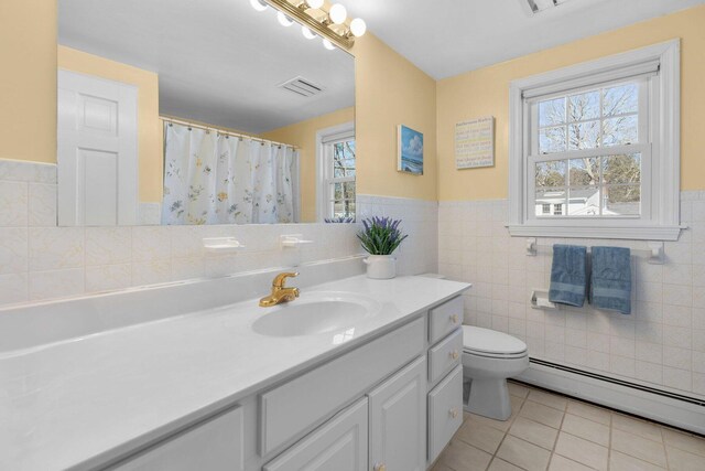 full bath featuring a wealth of natural light, a baseboard radiator, visible vents, and tile patterned flooring