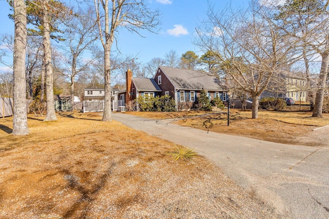 exterior space with driveway, a chimney, and fence