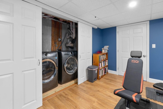 washroom featuring light wood finished floors, laundry area, baseboards, and washing machine and clothes dryer