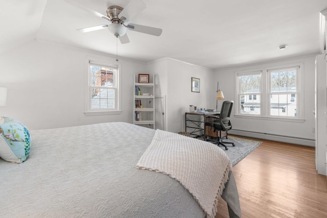 bedroom featuring multiple windows, a ceiling fan, baseboard heating, and wood finished floors