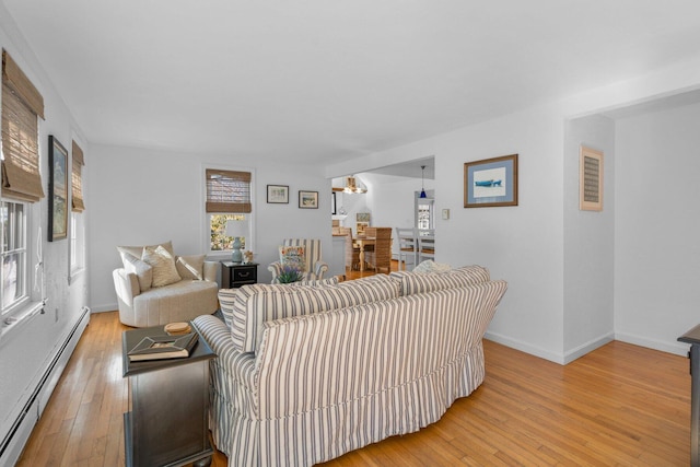 living area with baseboards, light wood finished floors, and baseboard heating