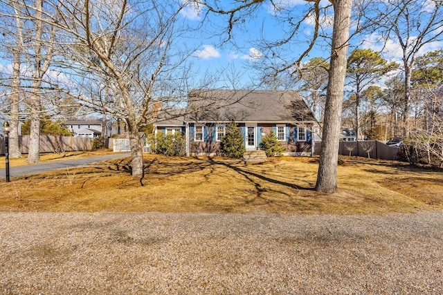 cape cod home featuring a front lawn and fence