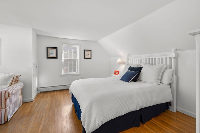 bedroom with a baseboard radiator, baseboards, lofted ceiling, and hardwood / wood-style floors