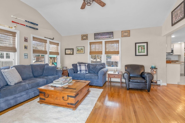 living area with light wood-style floors, ceiling fan, a baseboard heating unit, and vaulted ceiling