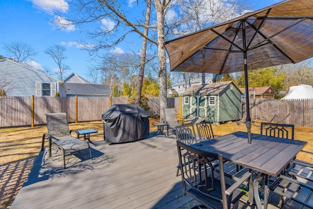 wooden deck with a fenced backyard, an outbuilding, grilling area, and outdoor dining space