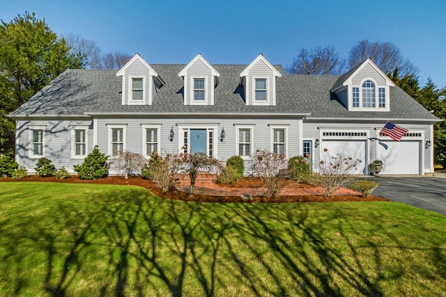 cape cod-style house featuring a front lawn, an attached garage, aphalt driveway, and roof with shingles