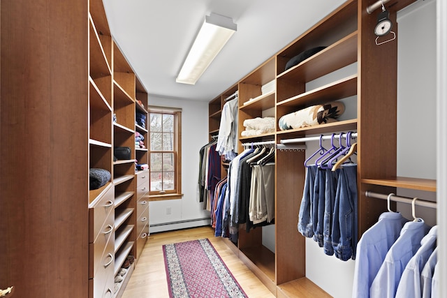 spacious closet with light wood finished floors and a baseboard heating unit