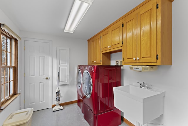 clothes washing area featuring baseboards, light tile patterned floors, separate washer and dryer, cabinet space, and a sink