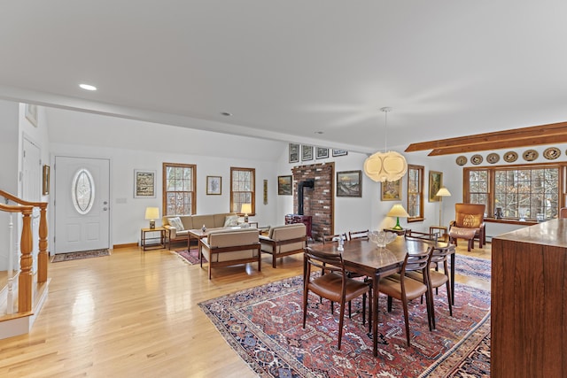 dining space featuring stairway, a wood stove, plenty of natural light, and light wood-style flooring