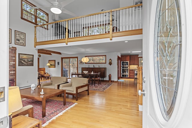 foyer featuring light wood-style flooring, a high ceiling, and ceiling fan