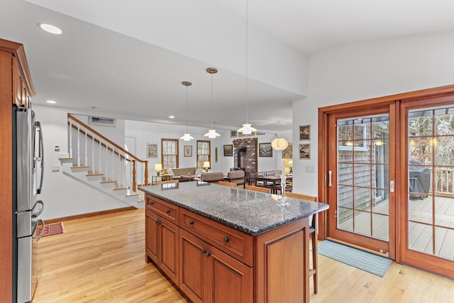 kitchen featuring light wood finished floors, recessed lighting, a kitchen island, and freestanding refrigerator