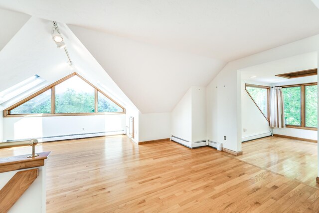 bonus room with a baseboard radiator, lofted ceiling, and light hardwood / wood-style flooring