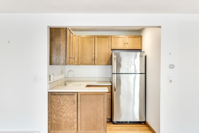kitchen featuring sink, light hardwood / wood-style floors, and stainless steel refrigerator