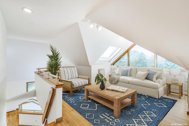 living room featuring vaulted ceiling with skylight and light hardwood / wood-style flooring