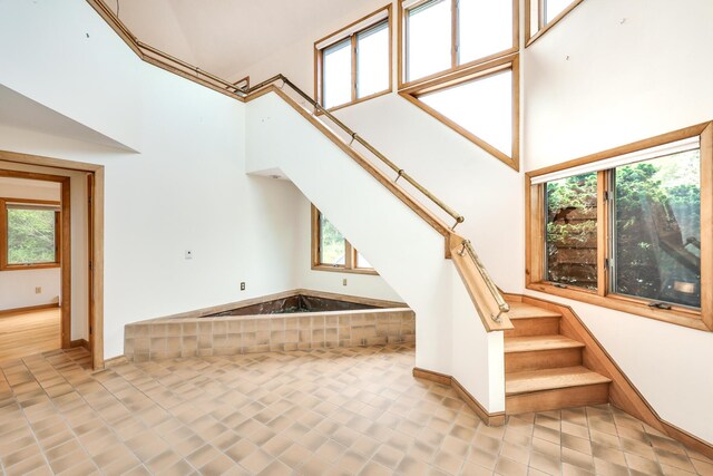 stairs with tile patterned flooring and a towering ceiling