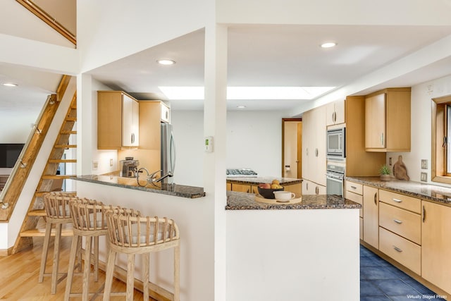 kitchen with dark stone countertops, light brown cabinets, and appliances with stainless steel finishes